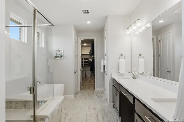 a spacious bathroom with a double vanity sink a mirror and shower