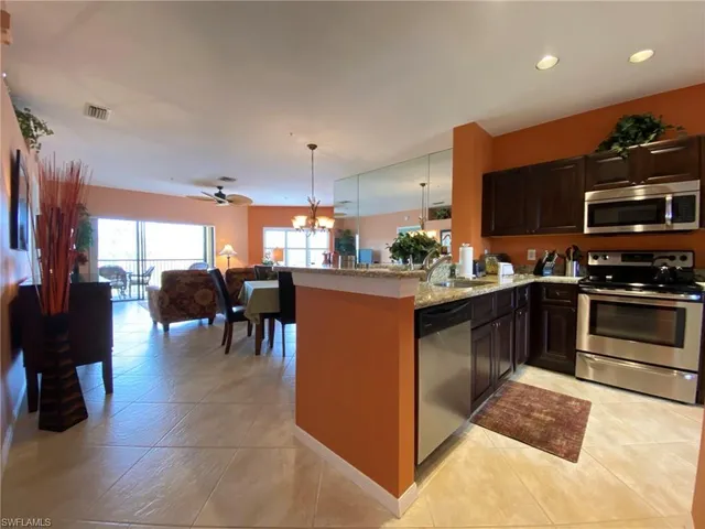 a kitchen with stainless steel appliances granite countertop a stove top oven a sink a dining table and chairs