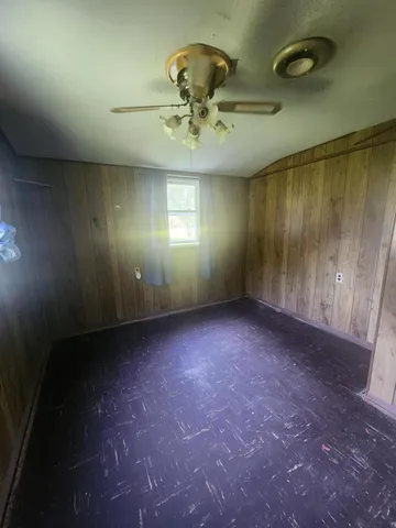 an empty room with a ceiling fan and window