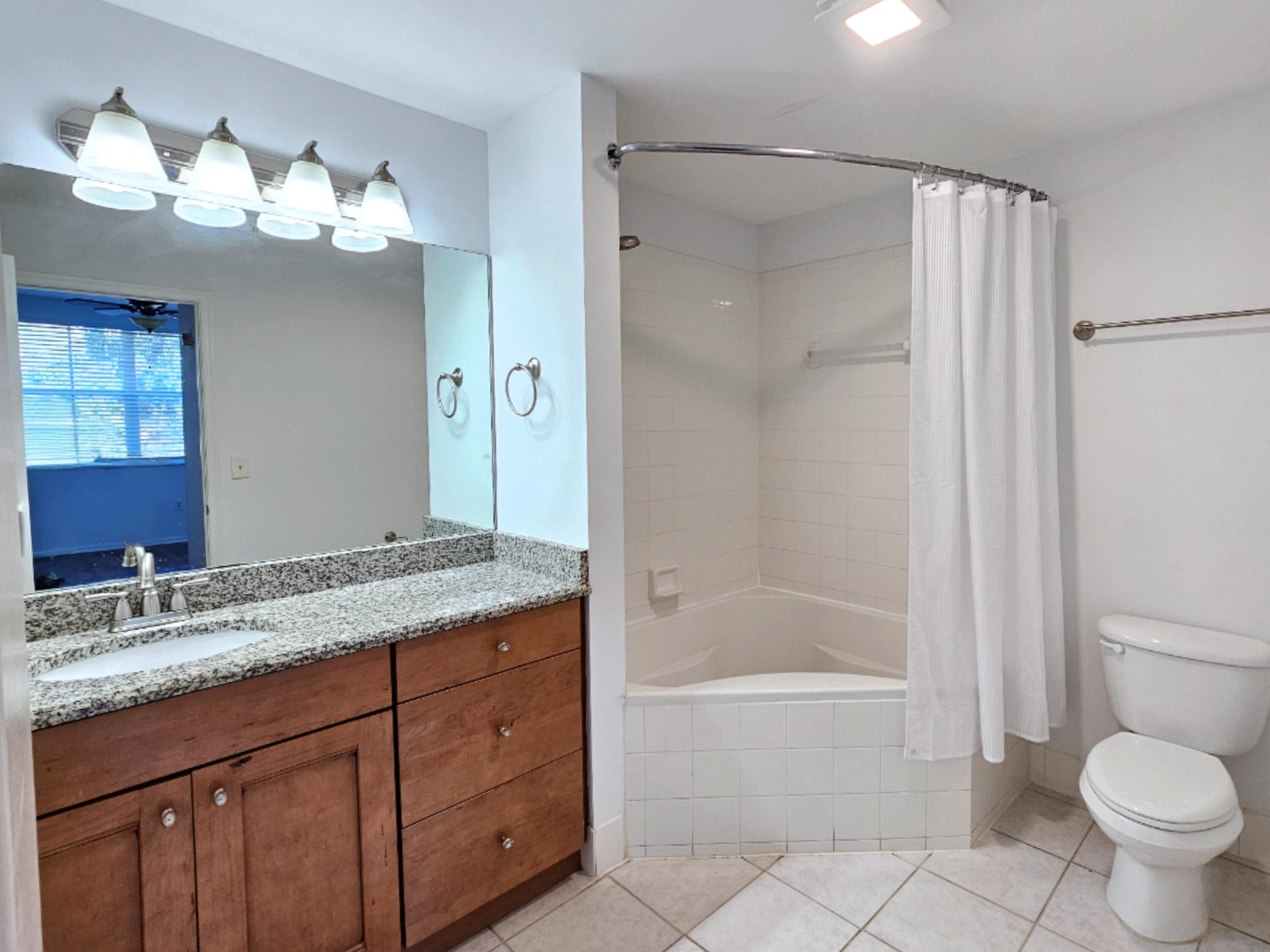 2020 Greenview Shores Boulevard, Unit 108 Wellington, FL 33414 - Photo 13 of 25 a bathroom with a granite countertop sink toilet and shower