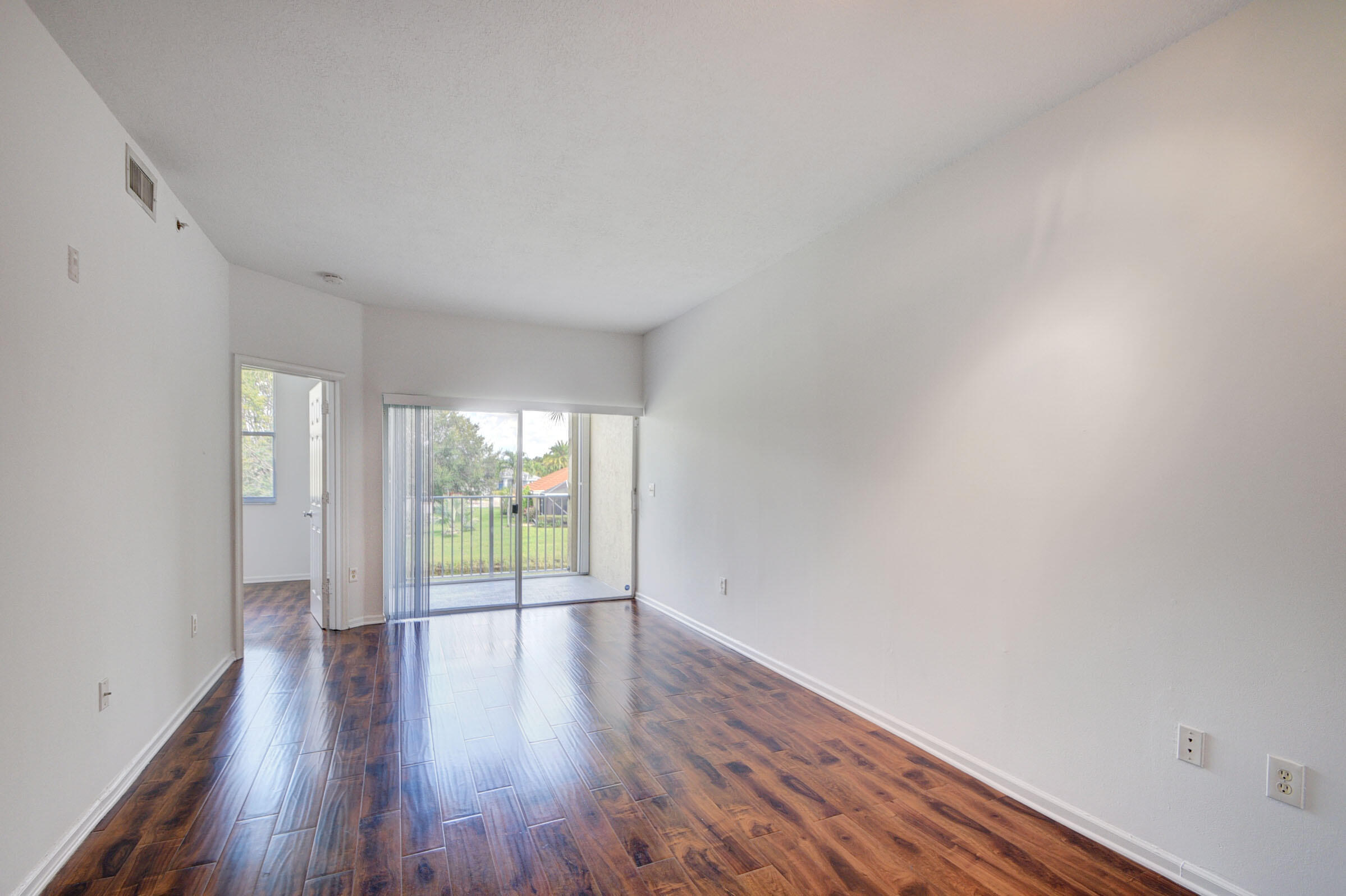 2020 Greenview Shores Boulevard, Unit 108 Wellington, FL 33414 - Photo 4 of 25 a view of an empty room with wooden floor and a window