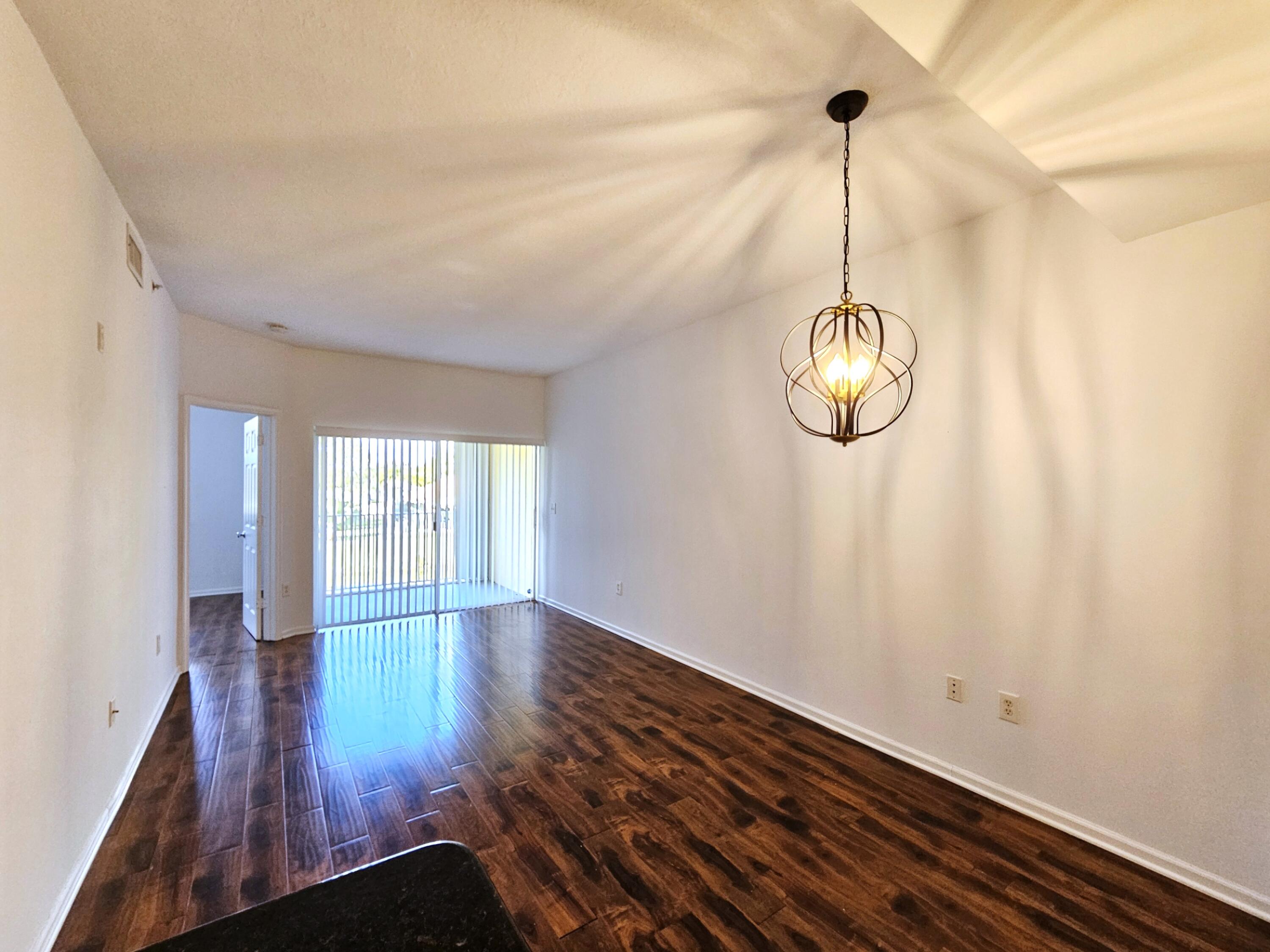 2020 Greenview Shores Boulevard, Unit 108 Wellington, FL 33414 - Photo 10 of 25 a view of empty room with wooden floor and fan