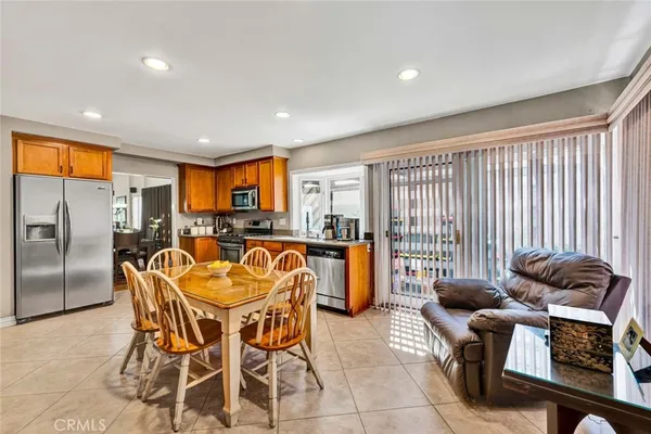 a kitchen with stainless steel appliances granite countertop a stove top oven a sink a dining table and chairs with wooden floor