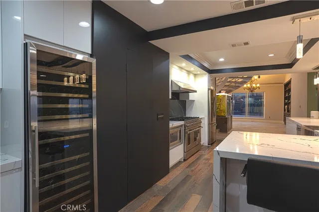 a room with stainless steel appliances kitchen island lots of furniture and wooden floor