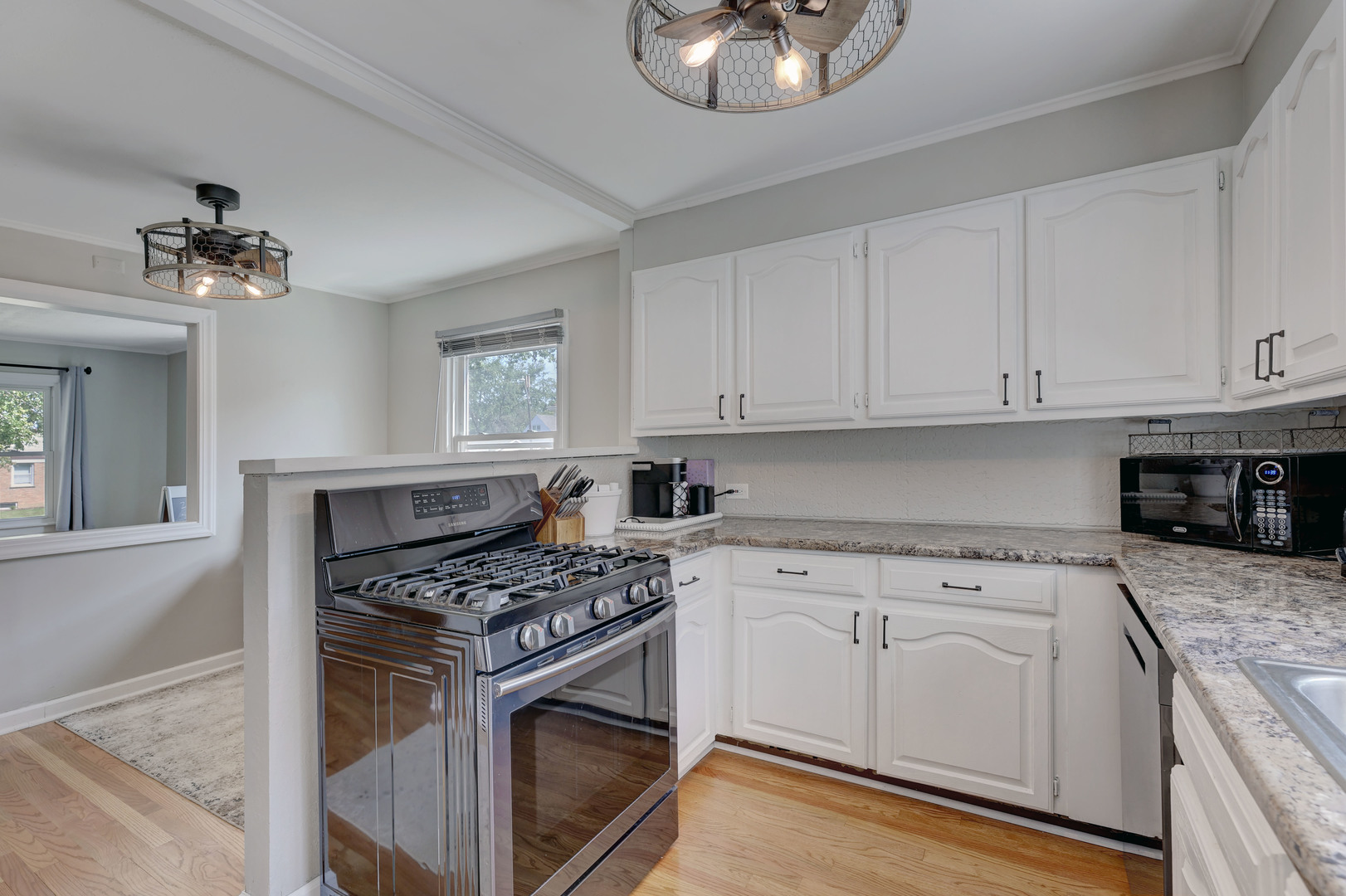 407 West Taylor Road Lombard, IL 60148 - Photo 11 of 33 a kitchen with granite countertop a stove a sink dishwasher and white cabinets with wooden floor