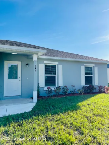 a front view of a house with a yard and potted plants