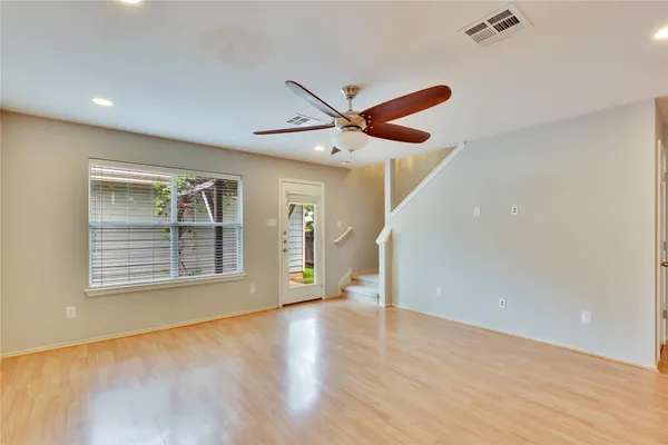 a view of an empty room with a window and wooden floor