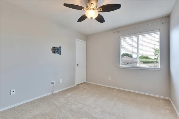 a view of an empty room with window and a ceiling fan