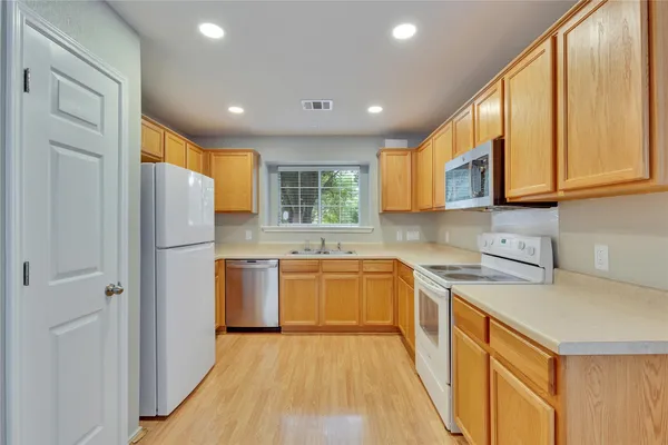 a kitchen with a refrigerator a sink and wooden cabinets