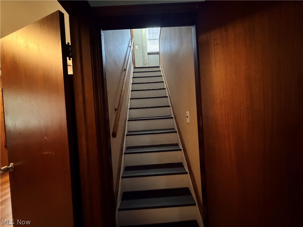 10506 Park Heights Road Cleveland, OH 44104 - Photo 16 of 22 Wooden staircase with white risers and dark treads, complemented by a light-toned wooden handrail