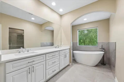 a spacious bathroom with a double vanity sink a large mirror and a bathtub
