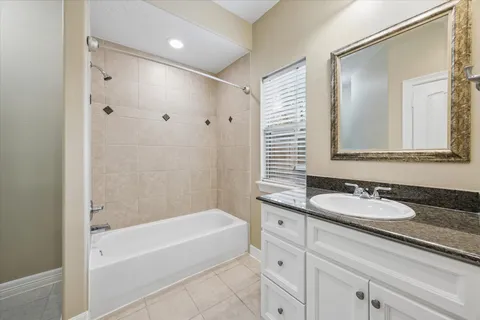 a bathroom with a granite countertop sink and a mirror a bathtub