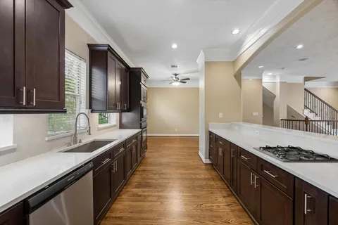 a large kitchen with stainless steel appliances a sink stove and cabinets