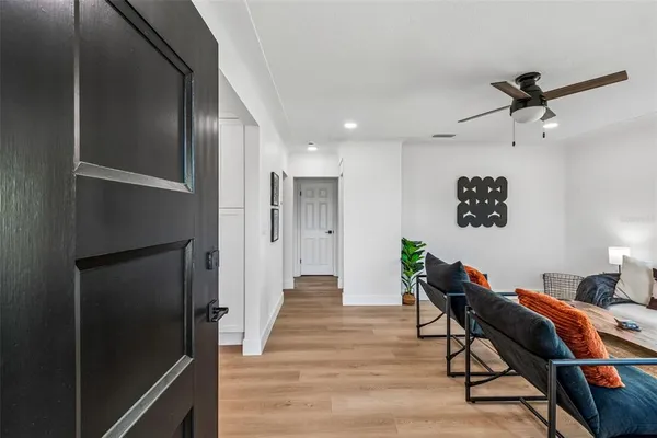 a kitchen with stainless steel appliances granite countertop a stove a sink a refrigerator white cabinets wooden floor and a window