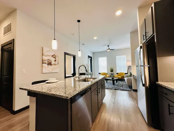 a kitchen with stainless steel appliances kitchen island granite countertop a table chairs sink and cabinets