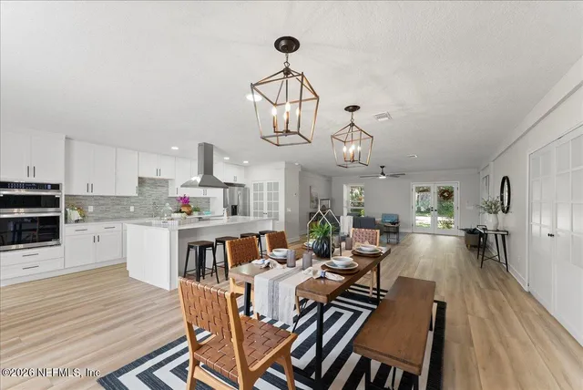 a view of a dining room and livingroom with furniture wooden floor a chandelier