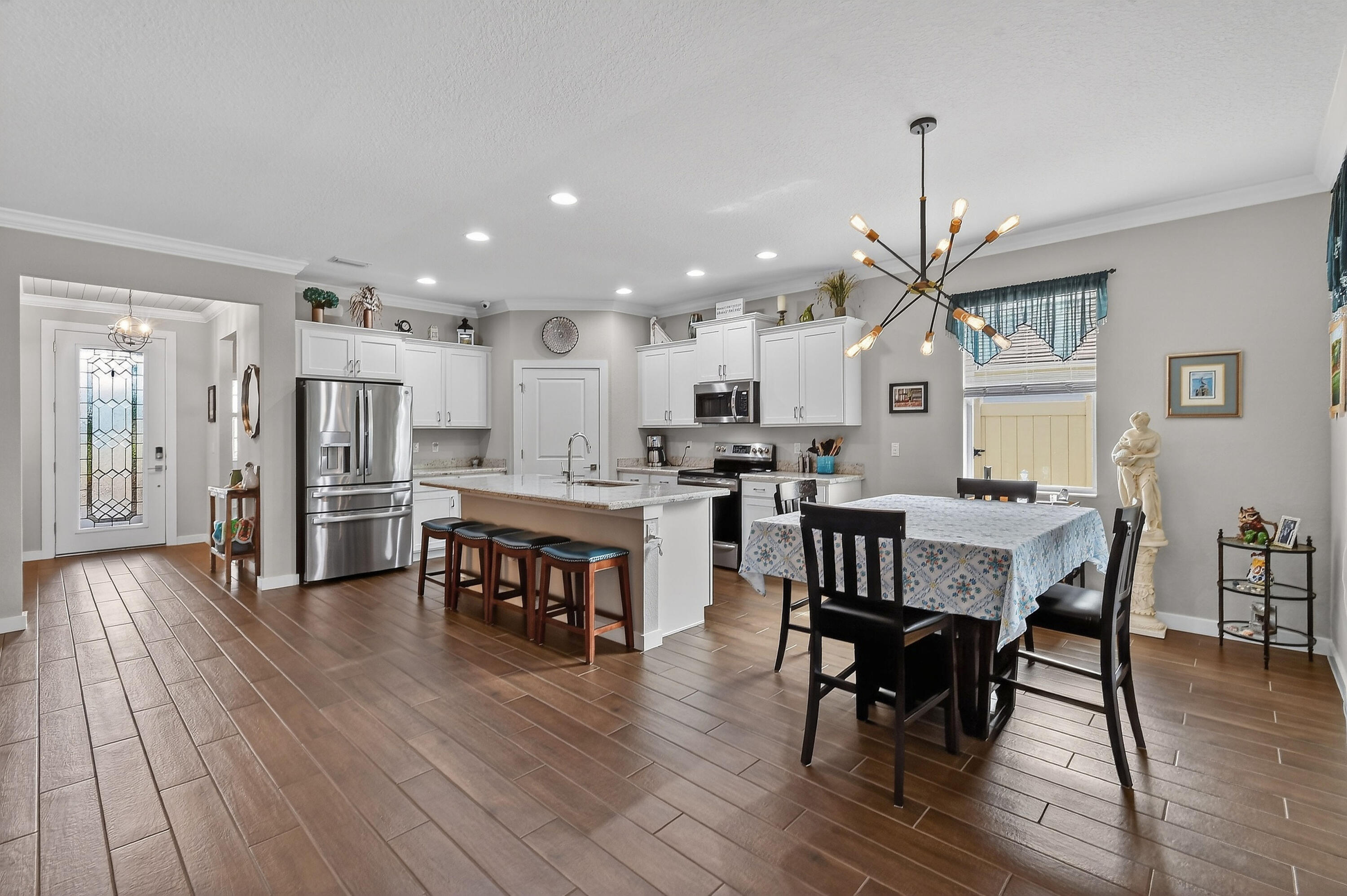 7561 Southwest Harbor Cove Drive Stuart, FL 34997 - Photo 21 of 62 a open kitchen with stainless steel appliances granite countertop a dining table chairs refrigerator and microwave