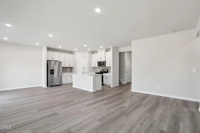 a view of kitchen with kitchen island wooden floor center island and stainless steel appliances