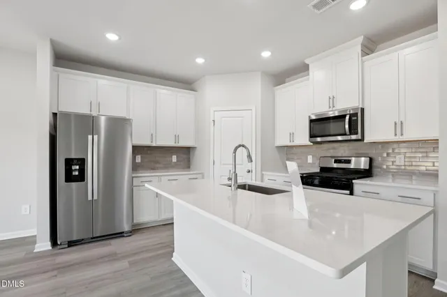 a kitchen with stainless steel appliances granite countertop a sink a stove a refrigerator a microwave and cabinets
