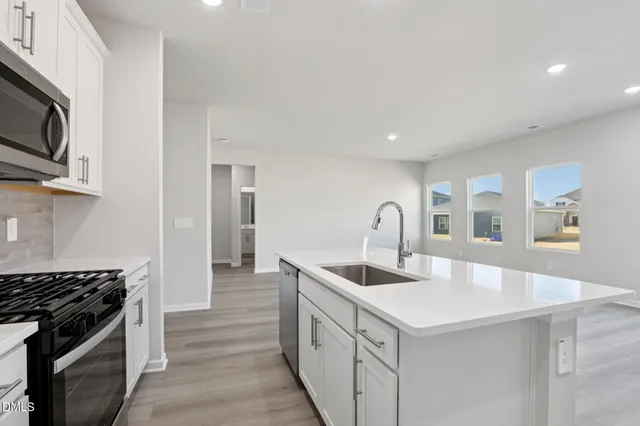 a kitchen with stainless steel appliances granite countertop a sink and a stove top oven with wooden floor