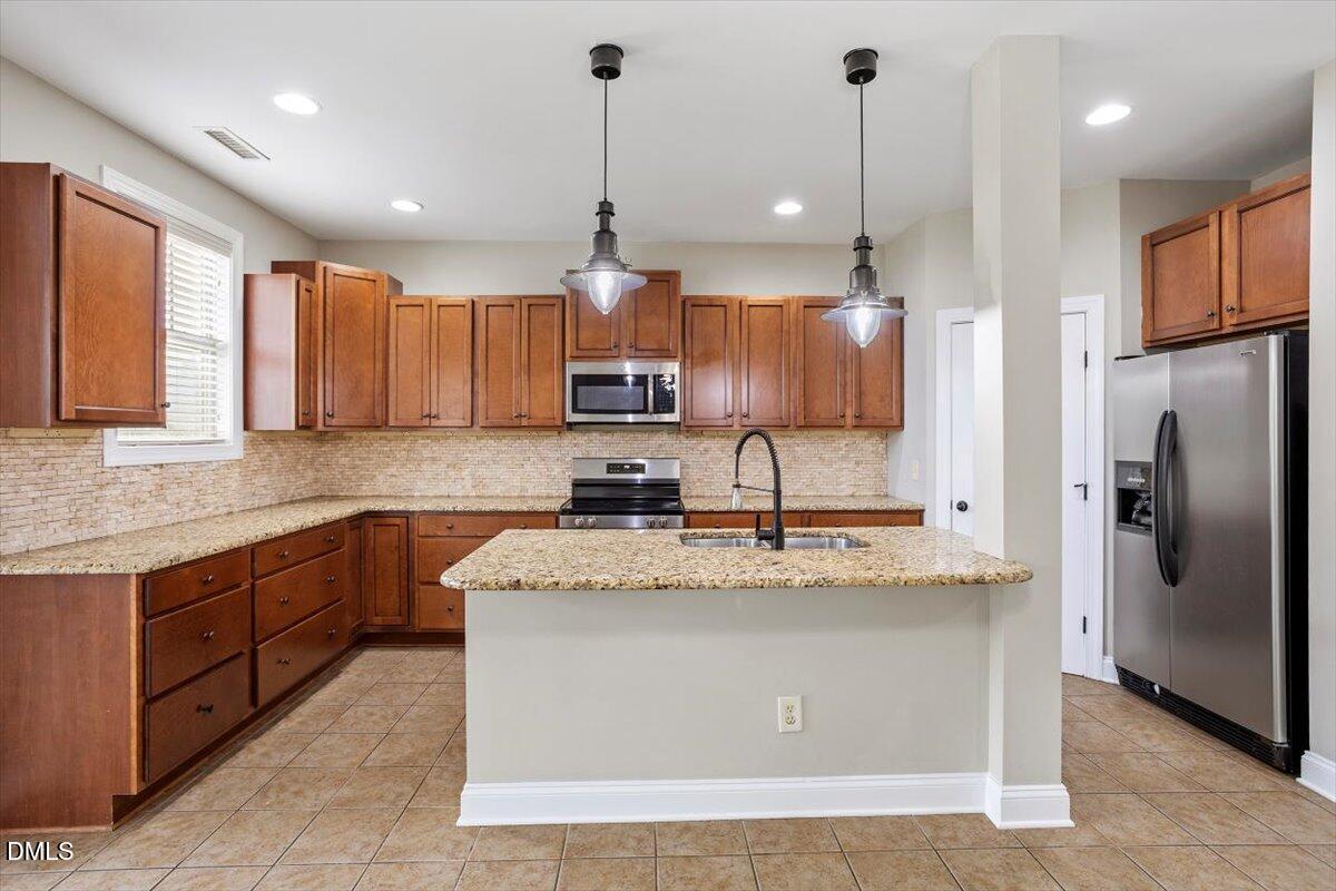 15 Crest Circle Garner, NC 27529 - Photo 12 of 41 a large kitchen with stainless steel appliances kitchen island granite countertop a refrigerator a sink a stove and a wooden cabinets