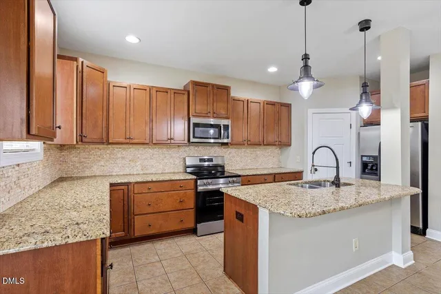 a kitchen with stainless steel appliances granite countertop a sink a stove and a wooden cabinets