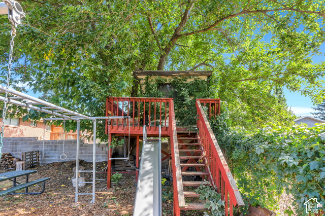 892 Bear Canyon Road Sandy, UT 84094 - Photo 31 of 36 Backyard featuring a red-stained wooden play structure with stairs, an attached slide, and an overhead monkey bar set