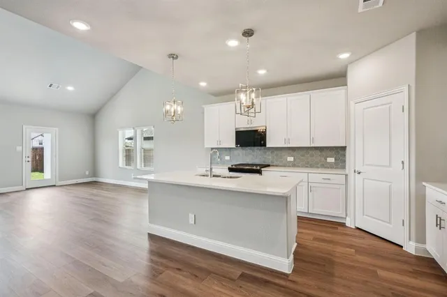 a kitchen with cabinets stainless steel appliances and wooden floor