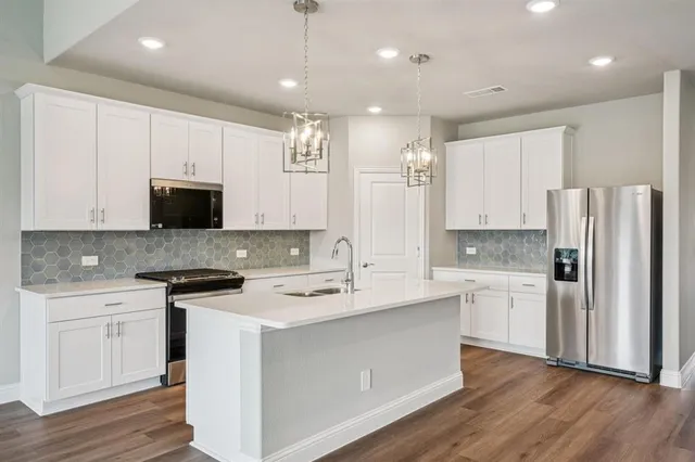a kitchen with a sink a stove a refrigerator and white cabinets