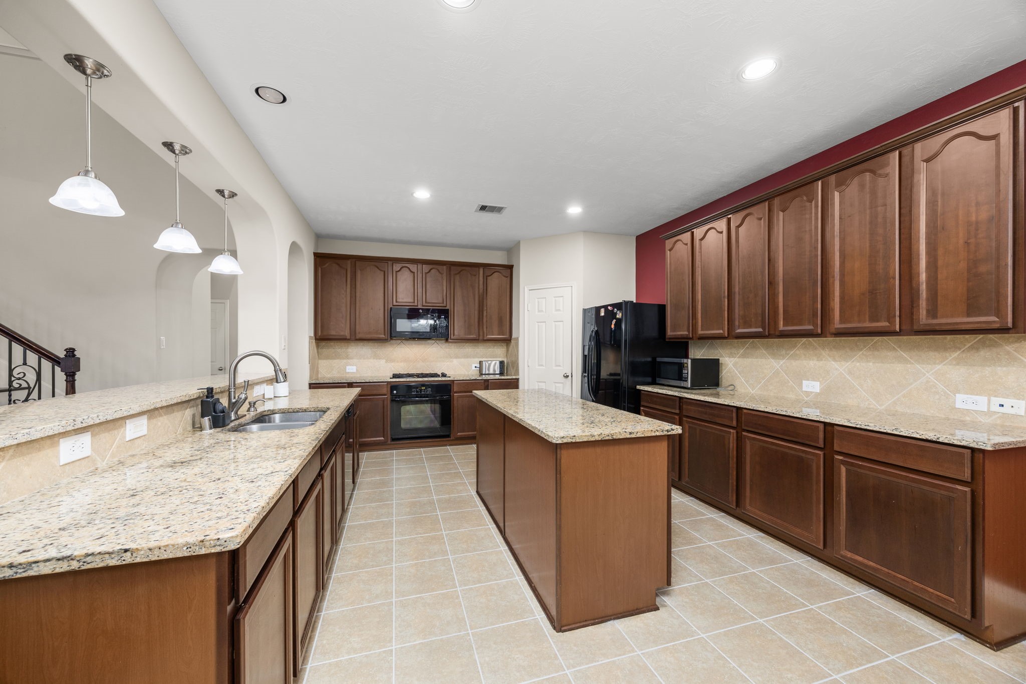 6719 Latchmore Lane Houston, TX 77049 - Photo 12 of 46 a kitchen with kitchen island granite countertop wooden cabinets a sink and dishwasher