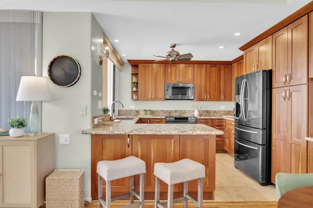 a kitchen with stainless steel appliances granite countertop a sink a stove a refrigerator and chairs