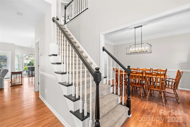 a kitchen with stainless steel appliances granite countertop a sink dishwasher a stove top oven a dining table and chairs with wooden floor