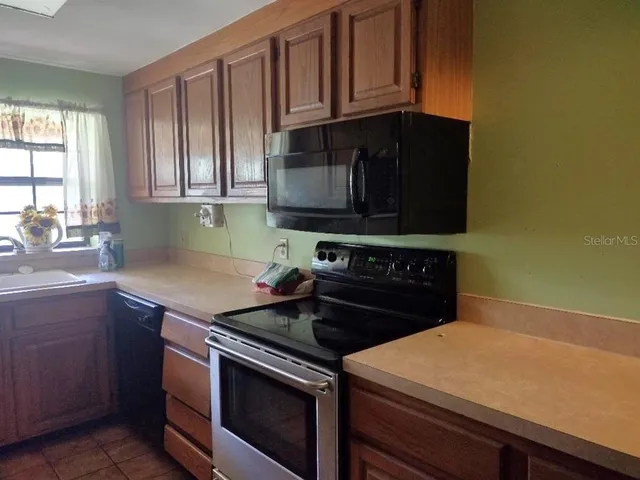 a kitchen with granite countertop a stove top oven microwave and cabinets