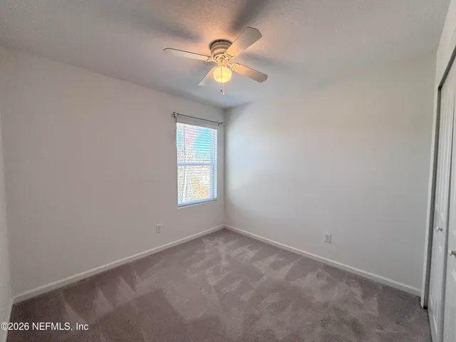 an empty room with a ceiling fan and a window