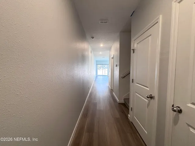a view of a hallway with wooden floor and closet