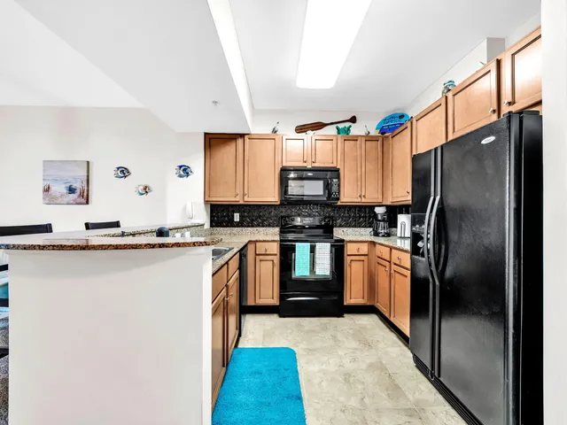 a kitchen with stainless steel appliances granite countertop a refrigerator a stove and a sink