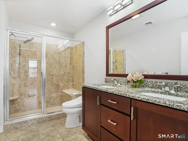 a bathroom with a granite countertop sink a toilet a mirror and shower