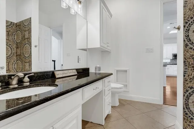 a bathroom with a granite countertop sink a toilet and a shower