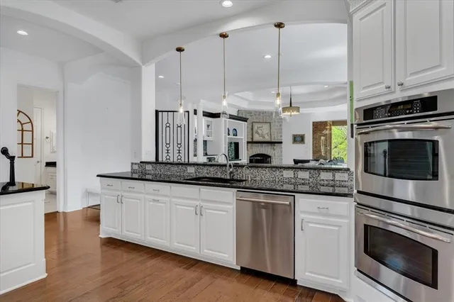 a kitchen with stainless steel appliances granite countertop a sink a stove and a wooden floors