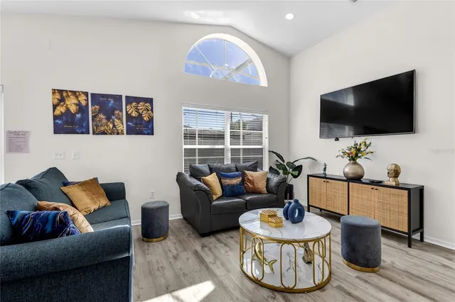 a living room with furniture a flat screen tv and a large window