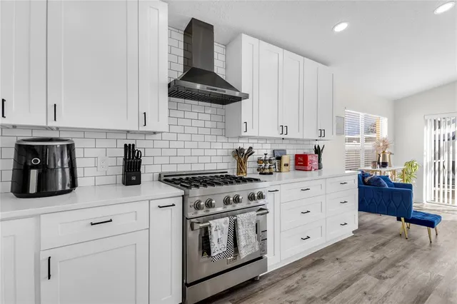 a kitchen with stainless steel appliances granite countertop a stove a sink and white cabinets