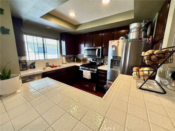 a kitchen with stainless steel appliances a sink a stove a refrigerator cabinets and a dining table