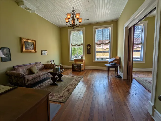 a view of a living room with wooden floors and kitchen view
