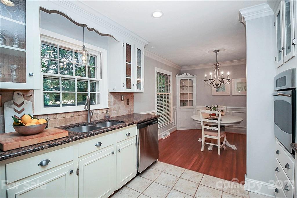 5620 Seacroft Road Charlotte, NC 28210 - Photo 14 of 36 a kitchen with granite countertop a stove a sink and a dining table with white cabinets
