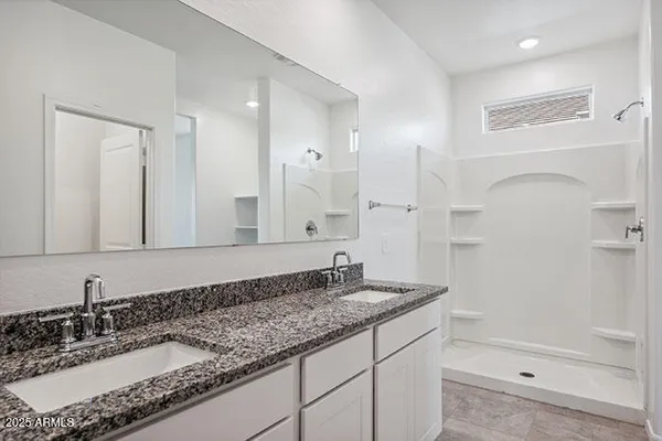 a bathroom with a granite countertop sink a mirror and shower