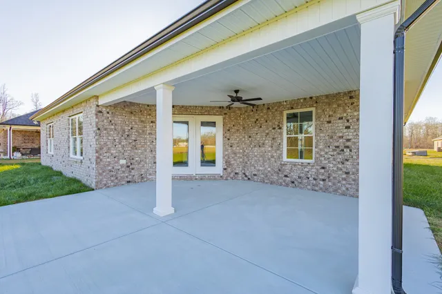 an empty room with wooden floor ceiling fan and windows