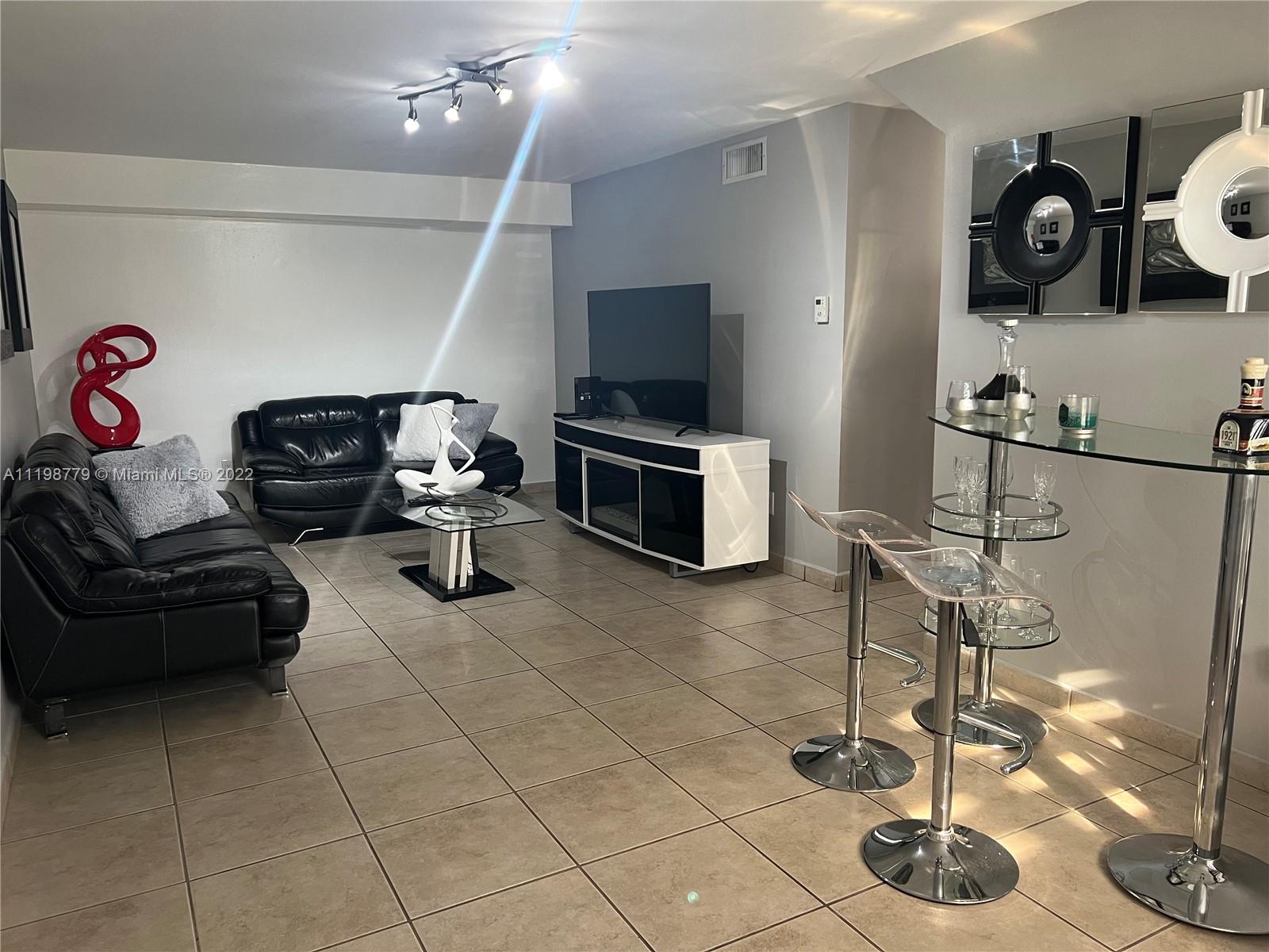 13983 Southwest 46th Terrace, Unit C Miami, FL 33175 - Photo 2 of 8 a living room with furniture and a flat screen tv