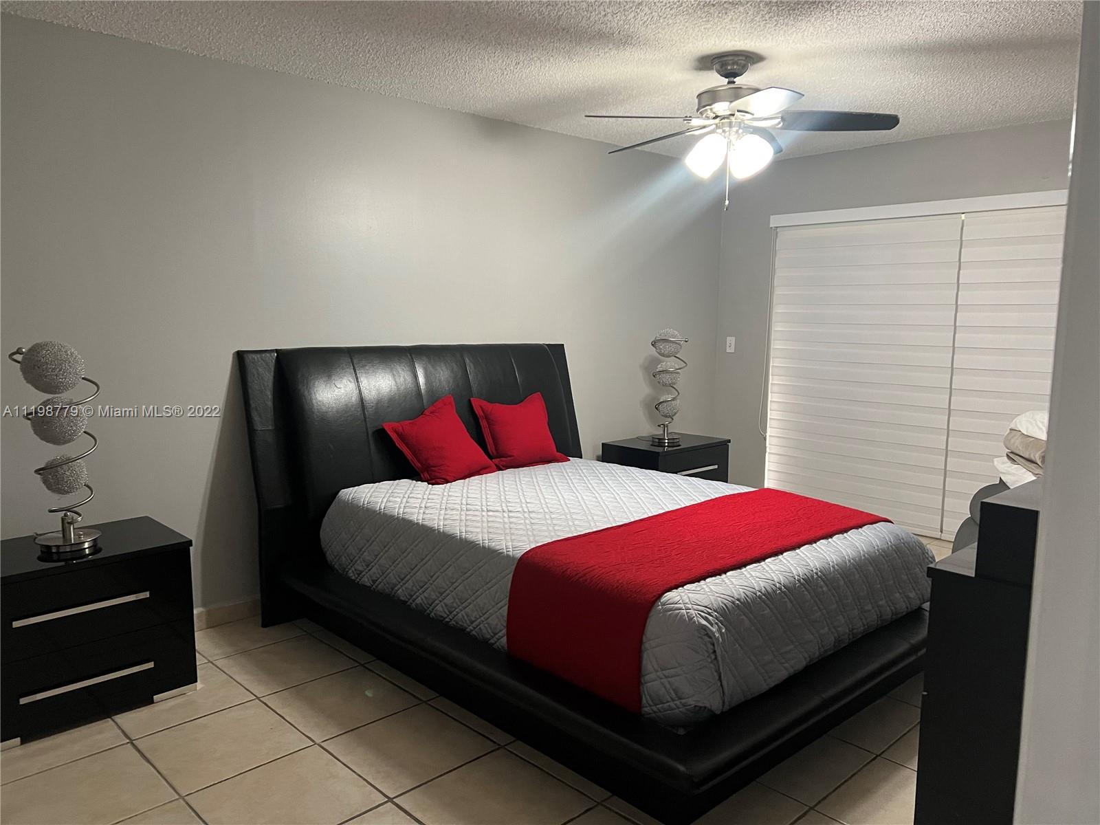 13983 Southwest 46th Terrace, Unit C Miami, FL 33175 - Photo 7 of 8 a bedroom with a bed and a chandelier