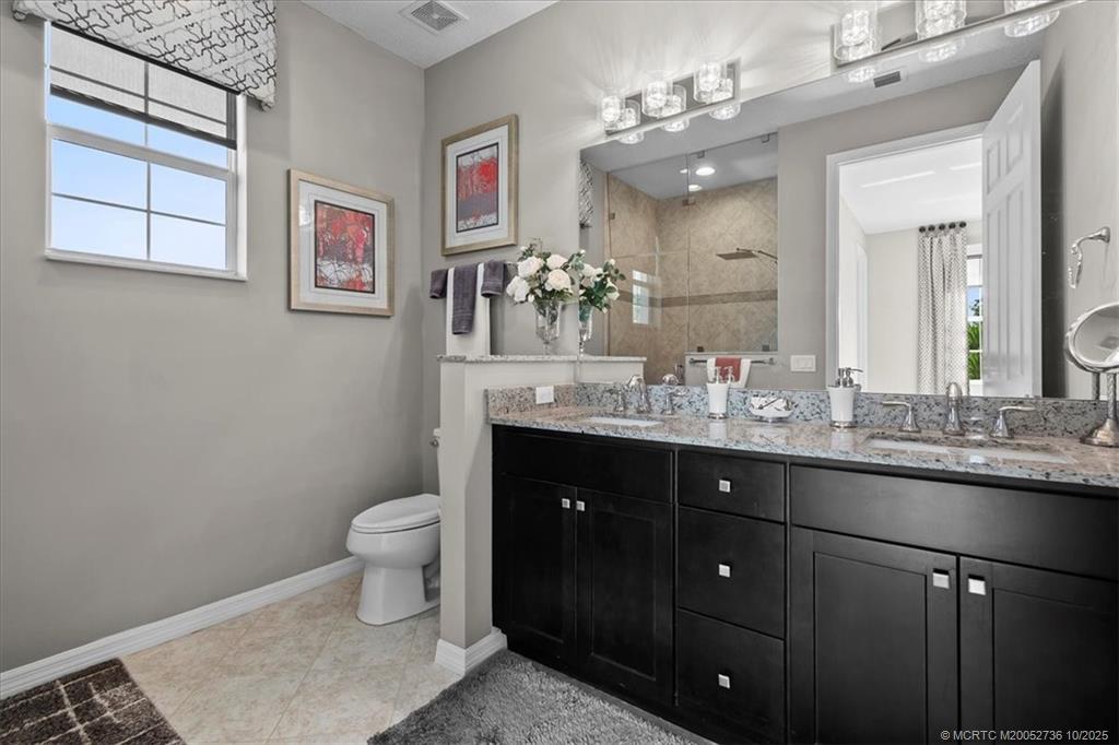 692 Southwest Glen Crest Way Stuart, FL 34997 - Photo 14 of 38 a bathroom with a toilet a sink and mirror