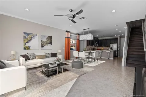 a living room with furniture kitchen view and a chandelier
